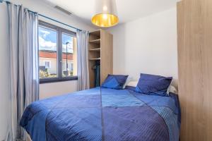 een slaapkamer met een blauw bed en een raam bij Rascola villa piscine 4 étoiles in Le Boulou +22 foto's