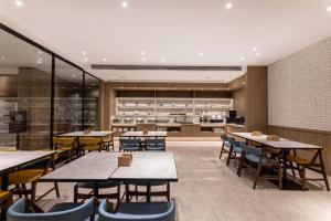 a restaurant with tables and chairs and a kitchen at Hanting Premium Hotel Taizhou Wanda Plaza in Taizhou
