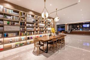 a dining room with a table and chairs and bookshelves at Hanting Premium Hotel Taizhou Wanda Plaza in Taizhou