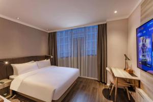 a bedroom with a white bed and a large window at Hanting Premium Hotel Taizhou Wanda Plaza in Taizhou