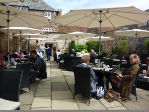 a group of people sitting at tables with umbrellas at The Swan Hotel, Wells, Somerset - The Coaching Inn Group in Wells