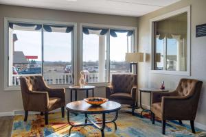 a waiting room with chairs and a table and windows at Super 8 by Wyndham Owatonna in Owatonna