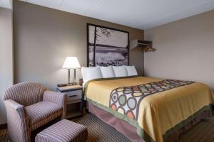 a hotel room with a bed and a chair at Super 8 by Wyndham Owatonna in Owatonna