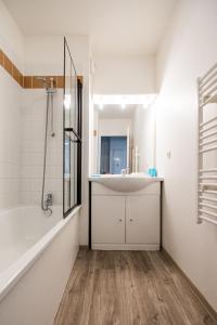 a bathroom with a tub and a sink and a shower at Le Bleu Turquoise in Équemauville
