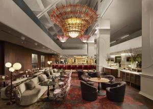 Le hall de l'hôtel est doté de tables, de chaises et d'un lustre. dans l'établissement Hilton Toronto, à Toronto