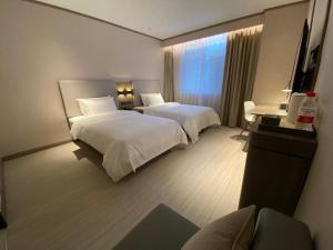 a hotel room with two beds and a window at Hanting Hotel Jining Jinyu Road in Jining