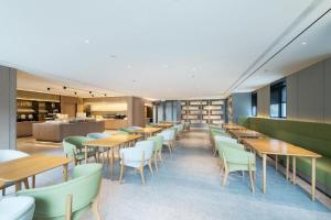 Ulan Hot的住宿－Ji Hotel Ulanhot Wanda Plaza，餐厅设有木桌和绿色椅子