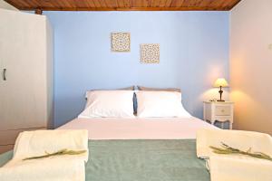 1 dormitorio con cama blanca y pared azul en Aoria Traditional House, en Loúlos