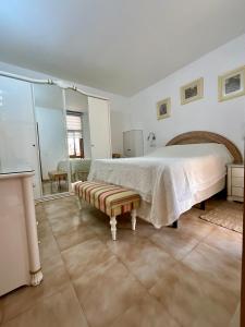 a white bedroom with a bed and a bench at Primavera in Costa Del Silencio