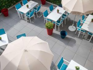 widok na patio ze stołami, krzesłami i parasolem w obiekcie ibis budget Menton Bord de Mer w Mentonie