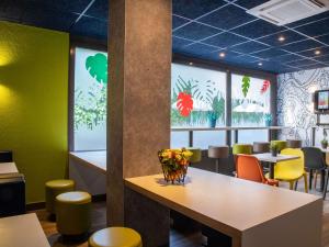 a dining room with a table and yellow chairs at ibis budget Menton Bord de Mer in Menton