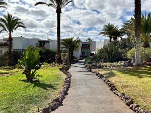 a walking path with palm trees and a building at Primavera in Costa Del Silencio