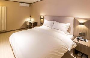 - un grand lit blanc dans une chambre d'hôtel dans l'établissement Hanting Hotel Shijiazhuang Shengli Bei Street, à Nangaoying