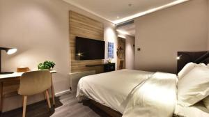 Dormitorio con cama, escritorio y TV en Hanting Premium Hotel Shanghai Puqingcheng Zhongxi Road en Qingpu
