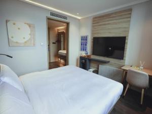 1 dormitorio con cama blanca, escritorio y TV en Hanting Premium Hotel Shanghai Puqingcheng Zhongxi Road en Qingpu