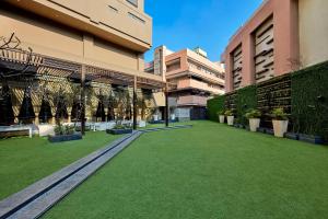 une cour d'un bâtiment avec de l'herbe verte et des plantes dans l'établissement DoubleTree by Hilton Gurugram Baani Square, à Gurgaon