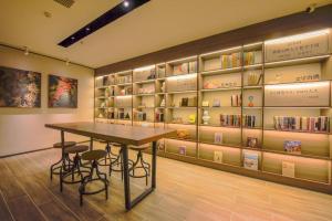 a room with a table and shelves of books at Hanting Hotel Shijiazhuang Xingtang Longzhou West Street in Xingtang
