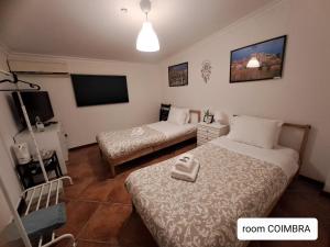 a bedroom with two beds and a flat screen tv at local 4 Dreams in Porto