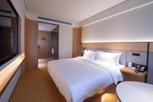 a hotel room with a large bed and a television at Ji Hotel Qingdao Shandong Road Mixc in Qingdao