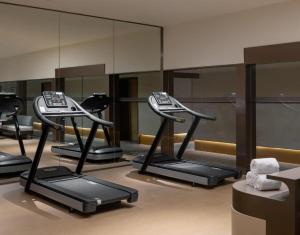 a row of exercise equipment in a room with mirrors at Ji Hotel Qingdao Shandong Road Mixc in Qingdao