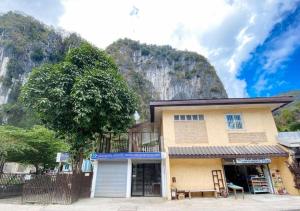 a building with a tree in front of a mountain at RedDoorz Hostel @ Bunakidz Lodge El Nido Palawan in Santa Monica