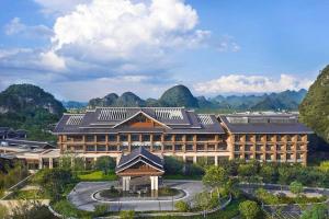 a large building with mountains in the background at Steigenberger Hotel SUNAC Jinan in Hongjialou