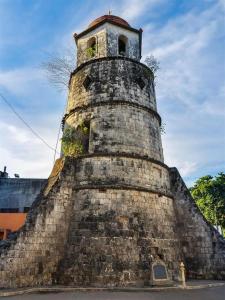 una vieja torre de ladrillo con un reloj en ella en Asia Novo Boutique Hotel-Dumaguete en Dumaguete