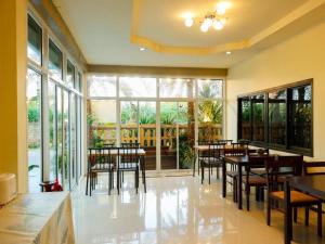AIRBEST HOTEL في Ban Chang: غرفة طعام بها طاولات وكراسي ونوافذ كبيرة