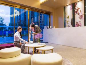 two people in a lobby with a table and chairs at Lavande Hotel Kunming Dianchi International Exhibition Center Guangfu Road in Kunming