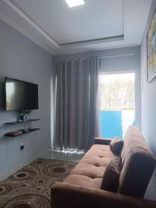 a living room with a couch and a large window at Kitnets Renascer Beach in Guaibim