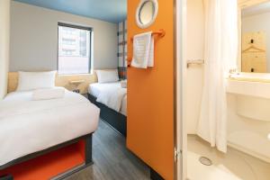 a small room with two beds and a sink at easyHotel Glasgow City in Glasgow