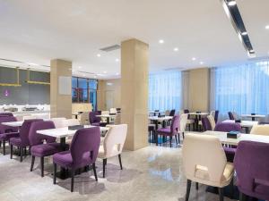 ShaoguanにあるLavande Hotel Shaoguan Bainian East Street Fengcai Buildingの紫と白の椅子とテーブルが備わるレストラン