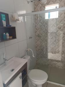 a bathroom with a toilet and a glass shower at Kitnets Renascer Beach in Guaibim