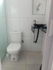 a white bathroom with a toilet and a sink at Kitnets Renascer Beach in Guaibim