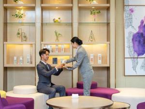 a man and a woman shaking hands in a room at Lavande Hotel Jieyang Danpu in Jieyang