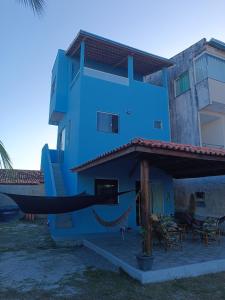 a blue house with a hammock in front of it at Kitnets Renascer Beach in Guaibim