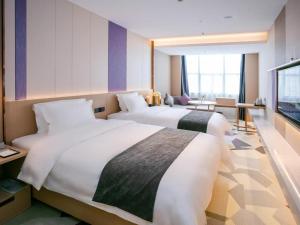 una camera d'albergo con due letti e una televisione di Lavande Hotel Huizhou World Trade Center a Huizhou