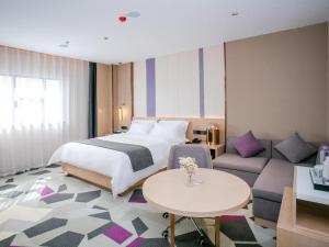 恵州市にあるLavande Hotel Huizhou World Trade Centerのベッドとソファ付きのホテルルーム