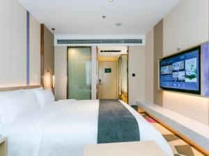 Lavande Hotel Huizhou World Trade Center في هويزو: غرفة فندقية بسرير وتلفزيون بشاشة مسطحة