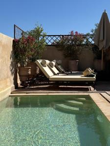 a swimming pool with a lounge chair and an umbrella at Riad Abracadabra in Marrakech