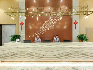 two people standing in a lobby with a large stage at Lavande Hotel Nanchong Xihua Shida in Nanchong