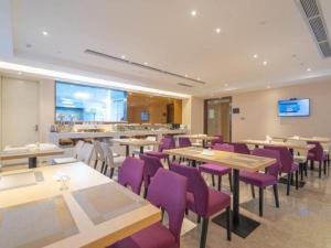 un restaurant avec des tables en bois et des chaises violettes dans l'établissement Lavande Hotel Huizhou Shiwan, à Shiwan