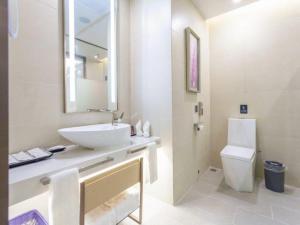 La salle de bains blanche est pourvue d'un lavabo et de toilettes. dans l'établissement Lavande Hotel Huizhou Shiwan, à Shiwan