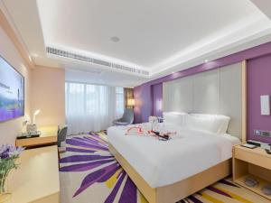 Cette chambre d'hôtel dispose d'un grand lit blanc et de murs violets. dans l'établissement Lavande Hotel Shenzhen Bay Houhai Avenue, à Shenzhen