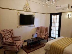 um quarto com uma cama, 2 cadeiras e uma mesa em Selborne Hotel em Bulawayo