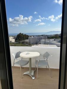 een witte tafel en 2 stoelen op een balkon bij OMIROS HOTEL in Mesariá