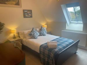 Un dormitorio con una cama con almohadas azules y una ventana en Luxury Country Bolthole Near Soho Farmhouse, en Middle Barton