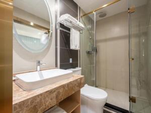 bagno con lavandino, servizi igienici e specchio di VX Hotel Beijing Daxing Wufutang Metro Station Zhongke Dianshanggu a Donggaodi
