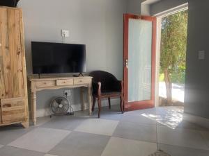 a room with a desk with a television and a chair at The Dunes Resort - Forest View in Plettenberg Bay