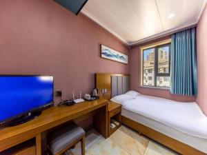 蘭州市にあるFERONIA Hotel Gansu Lanzhou Chengguan District Gannan Roadのベッド、デスク、薄型テレビが備わる客室です。
